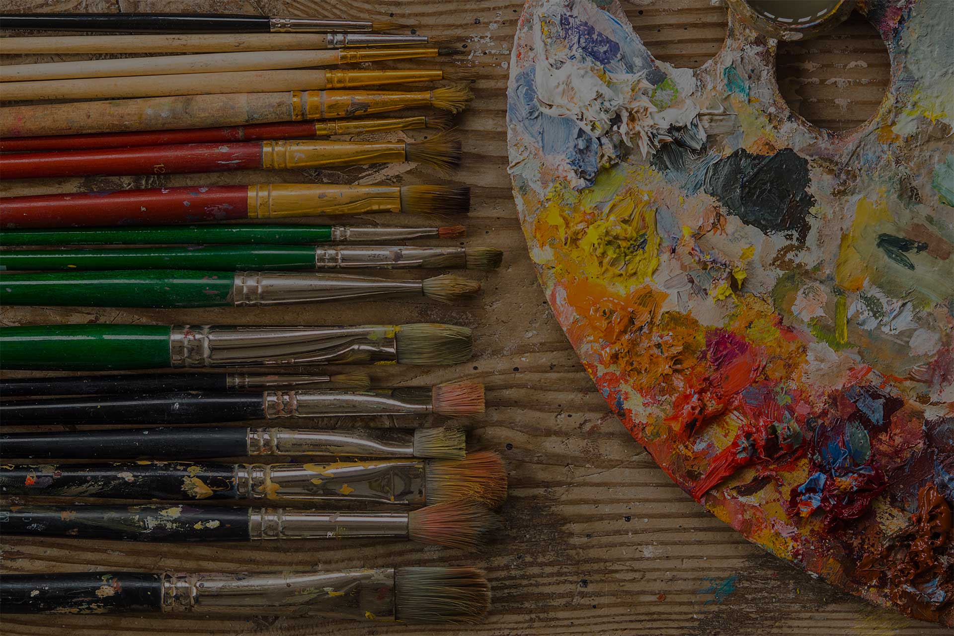 Color palette with different brushes on a wooden floor in a studio.